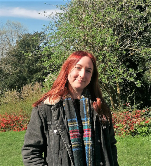 Subject Librarian Victoria Hopton standing outside in the sunshine in front of Royal Fort Gardens.